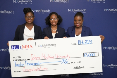 three students holding a large check