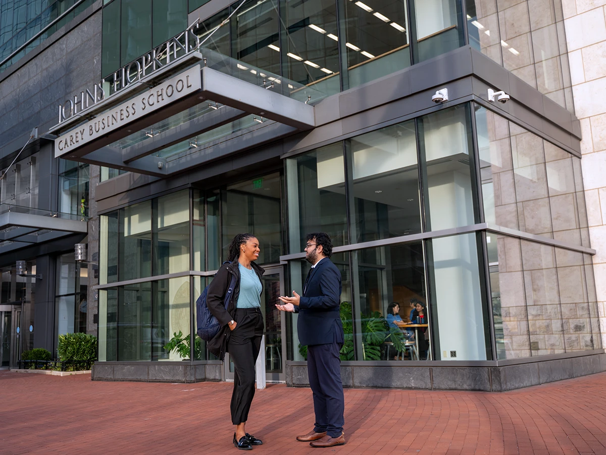 Two students at the entrance of Carey Business School building.