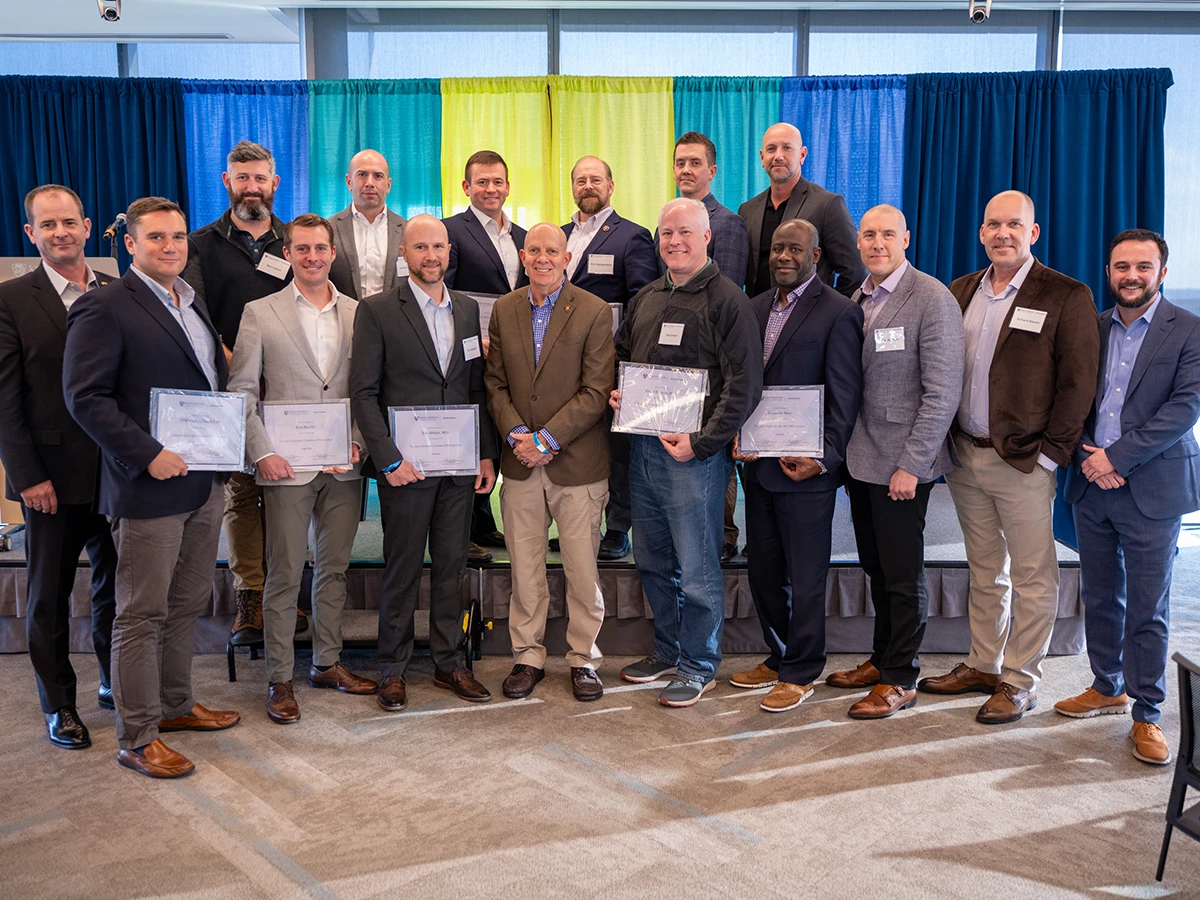 sixteen VET academy participants posing in a group photo holding the certificates
