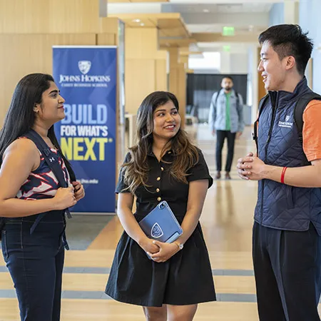 Three students talking in building lobby