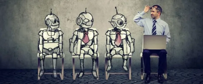 three robots and a man wearing a tie sitting in chairs