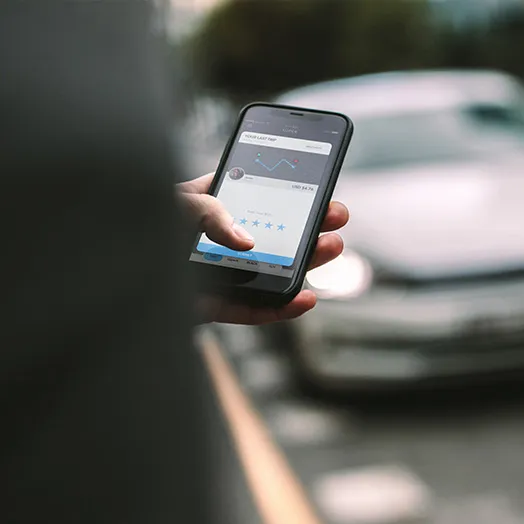 person with phone texting for a ride with a car in the background
