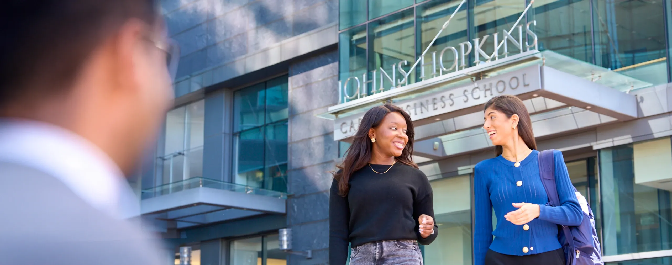 Students walking in front of the Carey Business School entrance in Baltimore.