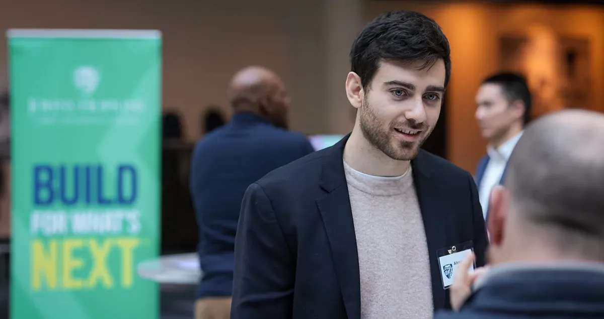Carey Business School alumni speaking to a staff member at a networking event.