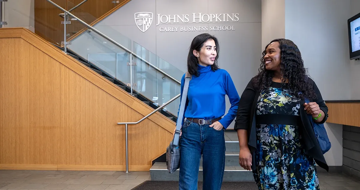 Two students walking in Carey Business School lobby.