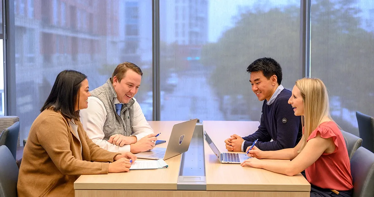 Student working together at a table in Carey Business School building.