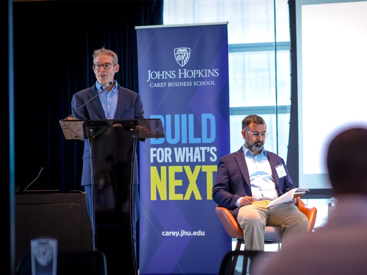 Professor Luca speaking from a podium and Carey Business school