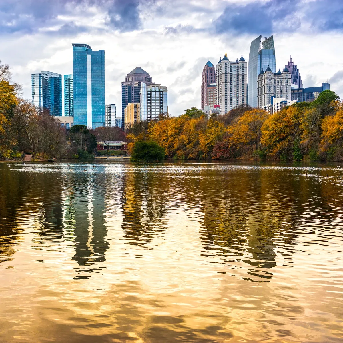 Atlanta skyline reflected in lake at autumn, with golden trees and blue sky