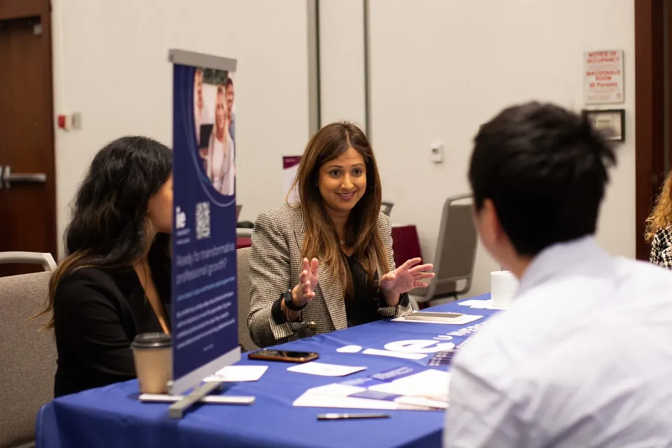 Woman at table speaking to two people during an information session