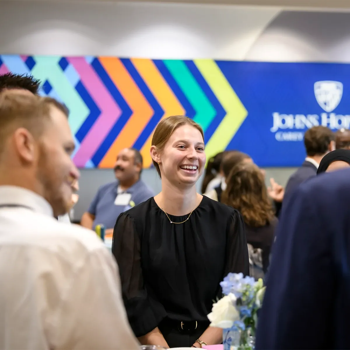 Smiling woman at conference with Carey signage in background