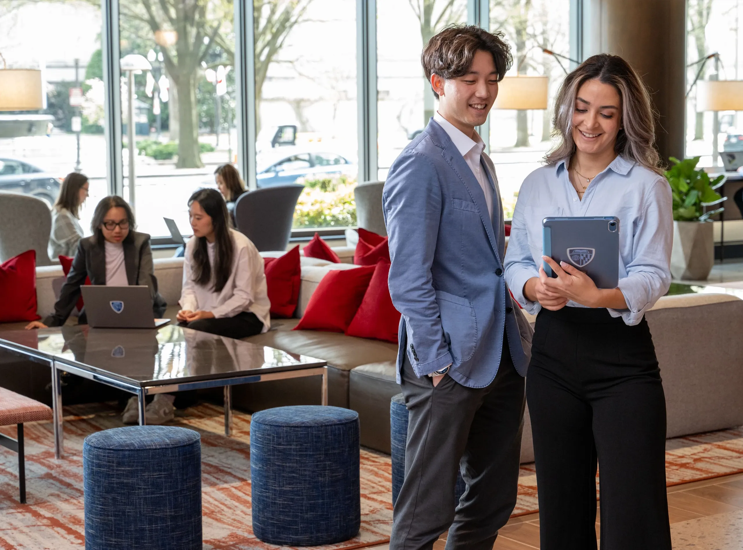 Two students smiling with a tablet in a modern lounge