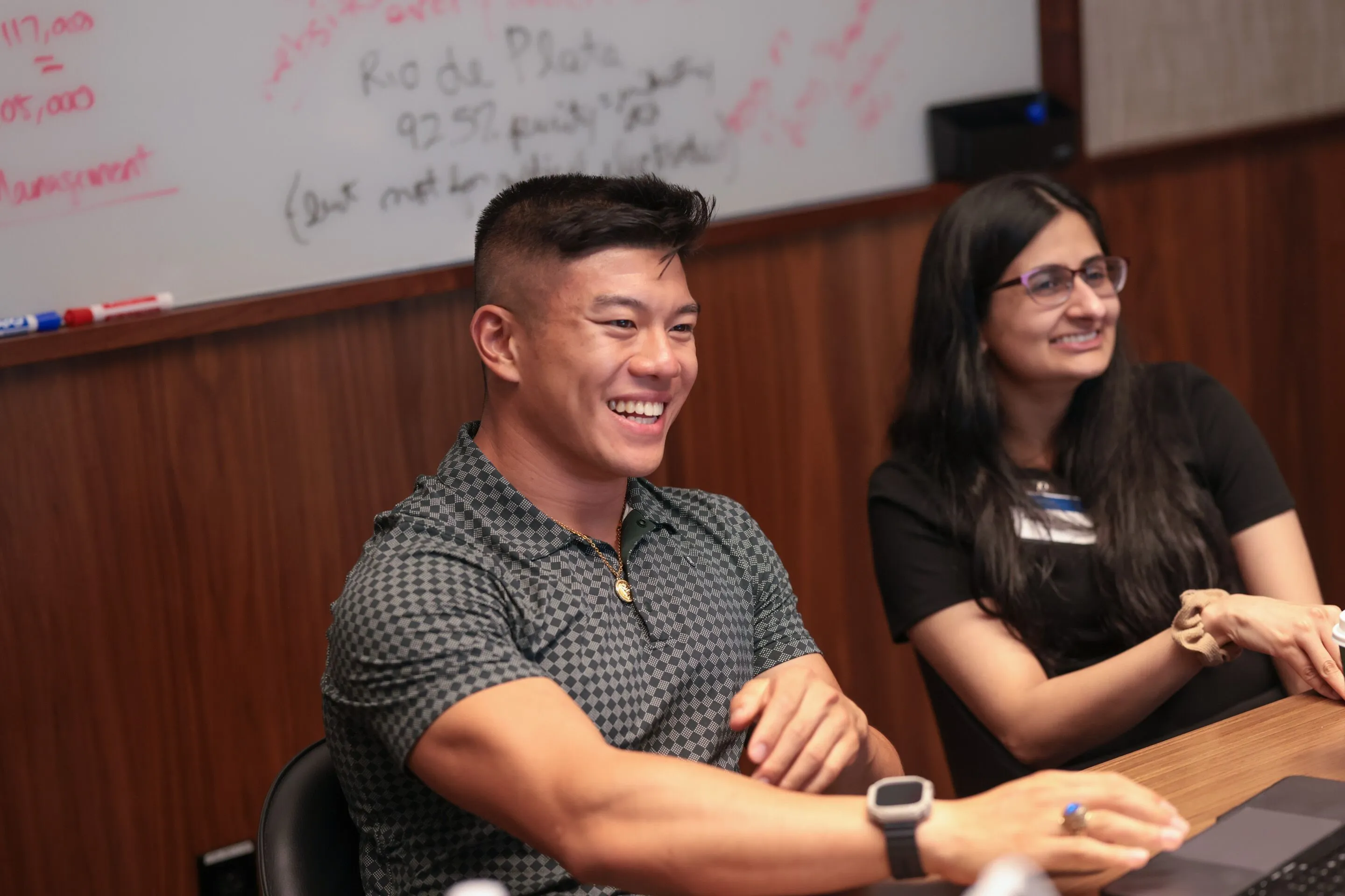 Students working together and smiling while staring at a computer