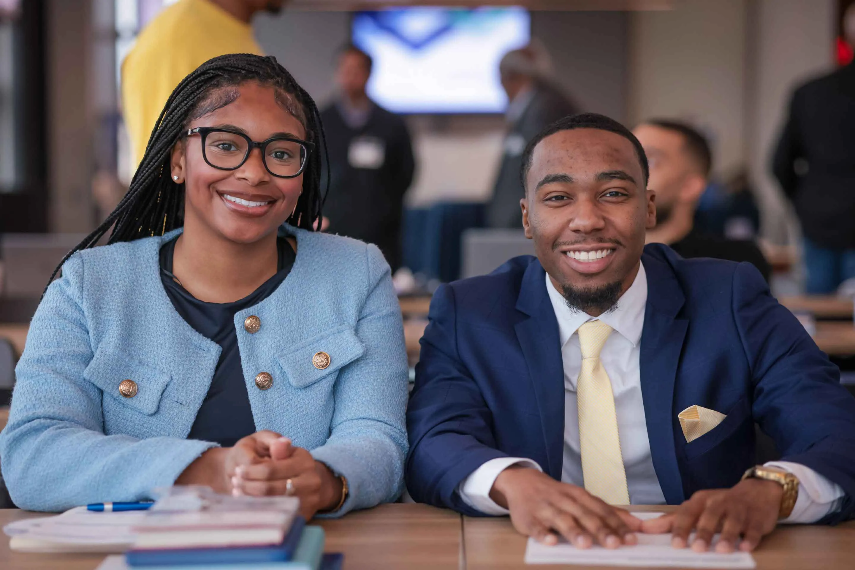 Two students sitting at the desk and smiling at the camera