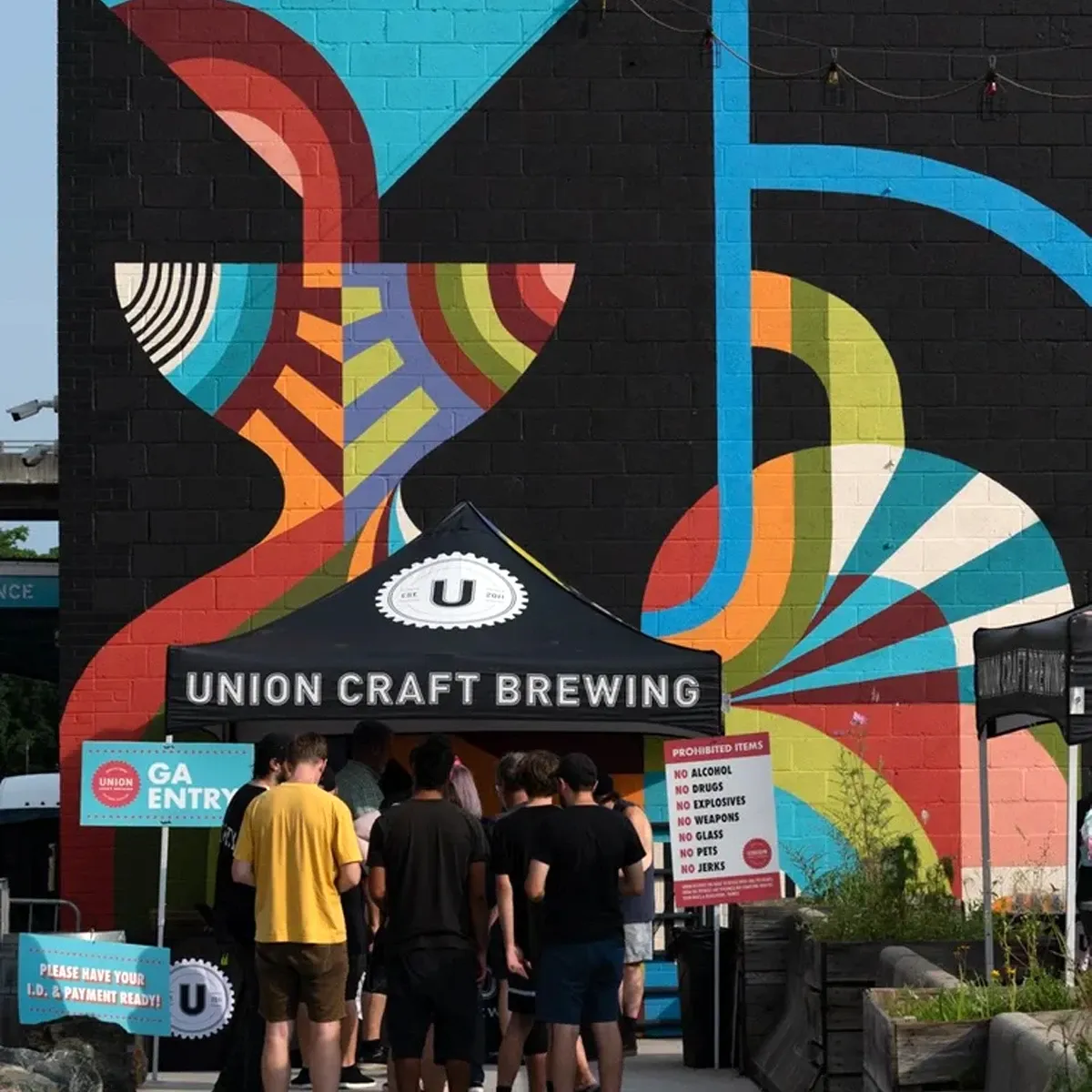 Group of people entering Union Craft Brewing beneath colorful abstract mural