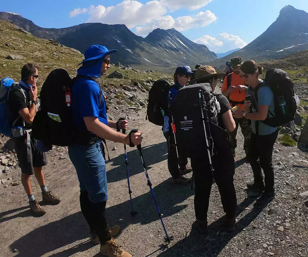 a group of students with full backpacks hiking in the mountains