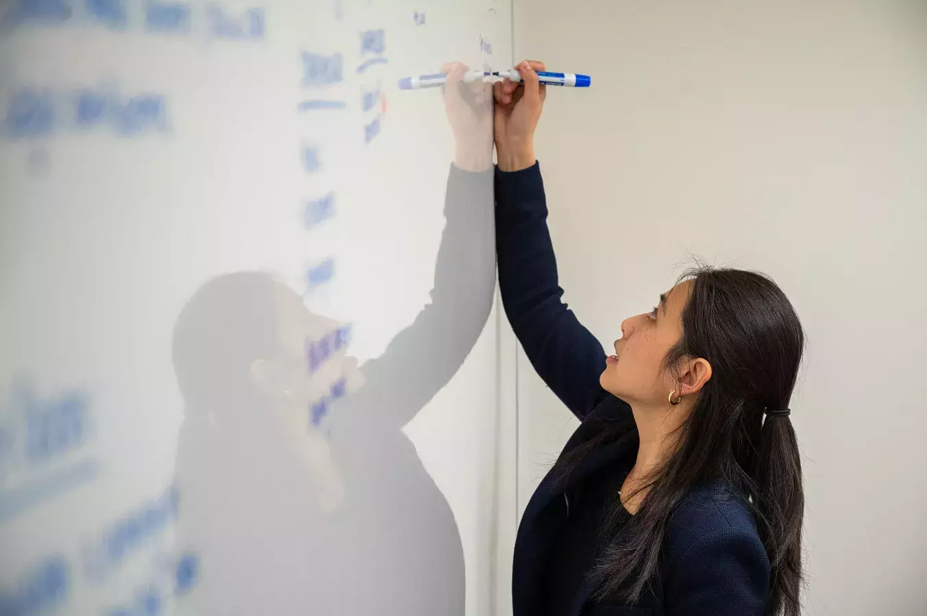cil person writing with an erasable marker on a board