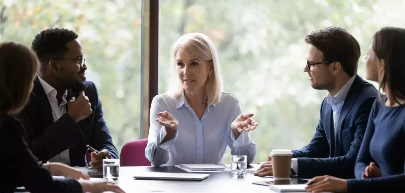 a group of people sitting at a table with a leader discussing management concepts