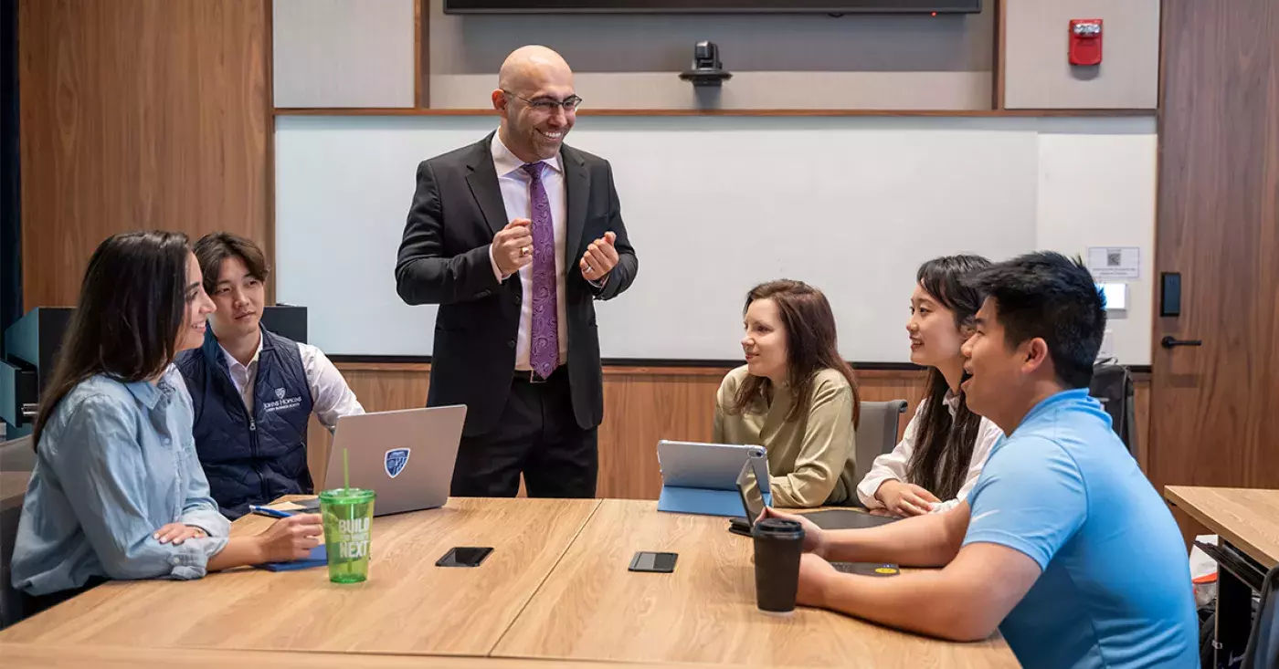 instructor talking to students sitting at a table