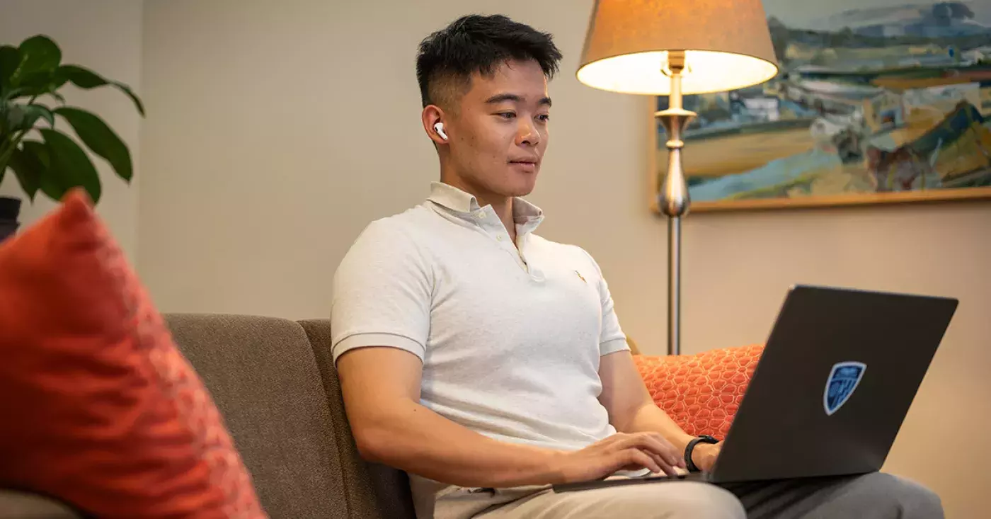 student sitting in chair with laptop