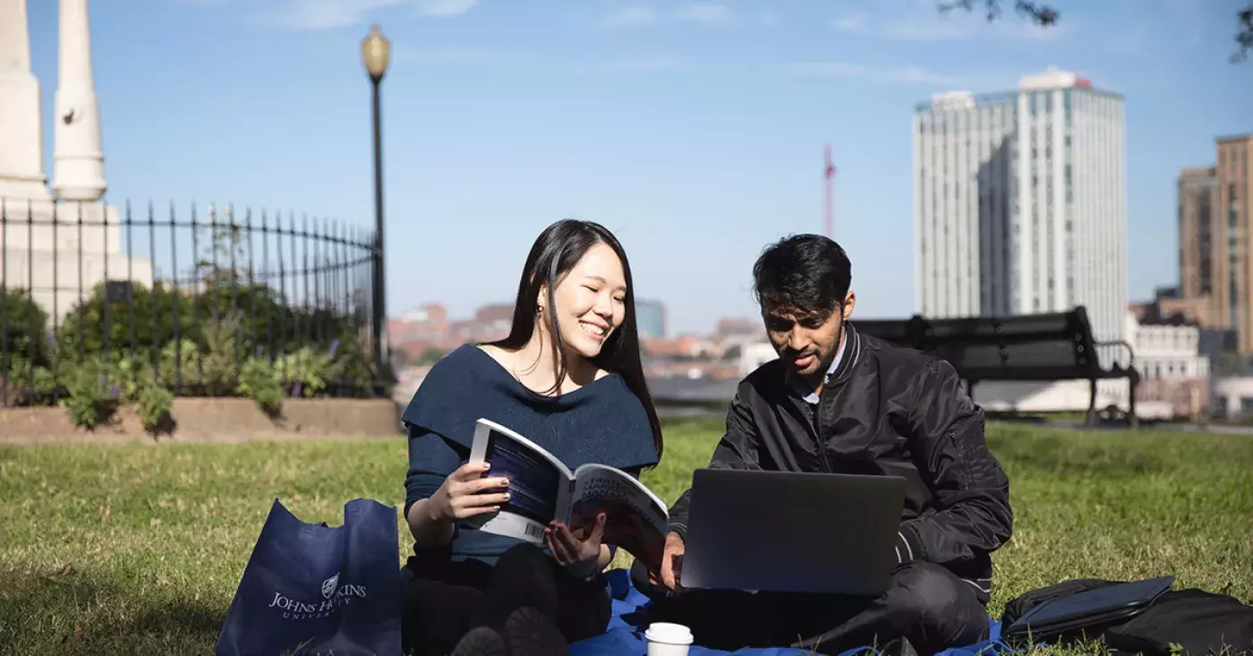 two students sitting looking at a laptop