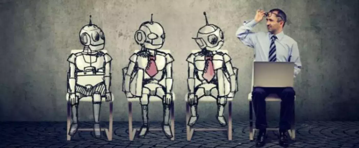 three robots and a man wearing a tie sitting in chairs