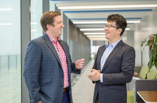 two johns hopkins carey business school alums stand talking as they prepare for alumni weekend 2019