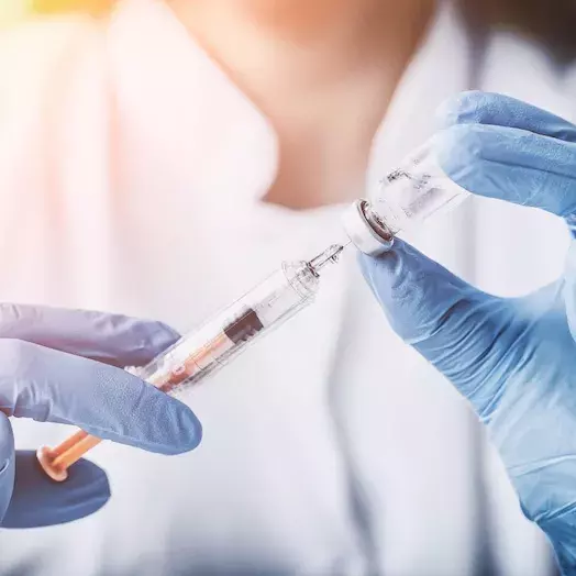 woman holding up a vaccine in her hands