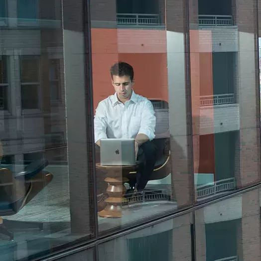 young male adults researching on his computer about GMAT/GRE waivers at Johns Hopkins Carey Business School.