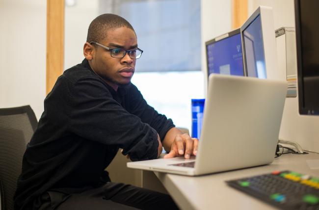 student sitting at his computer, working on his online MBA