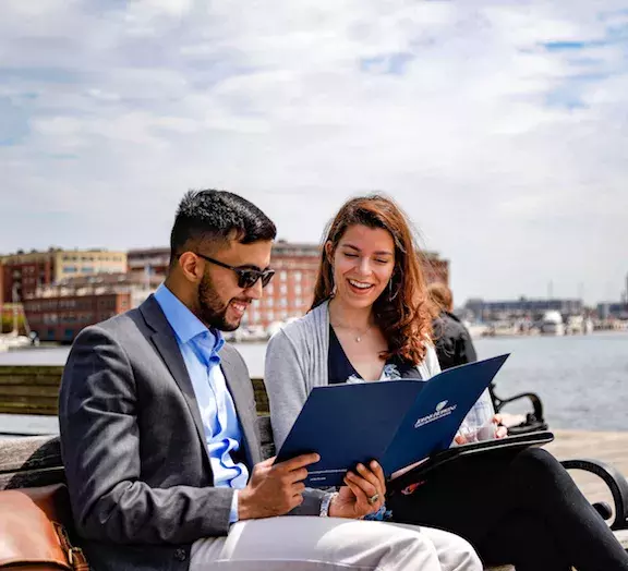 two students looking at a folder of programs at johns hopkins carey business school