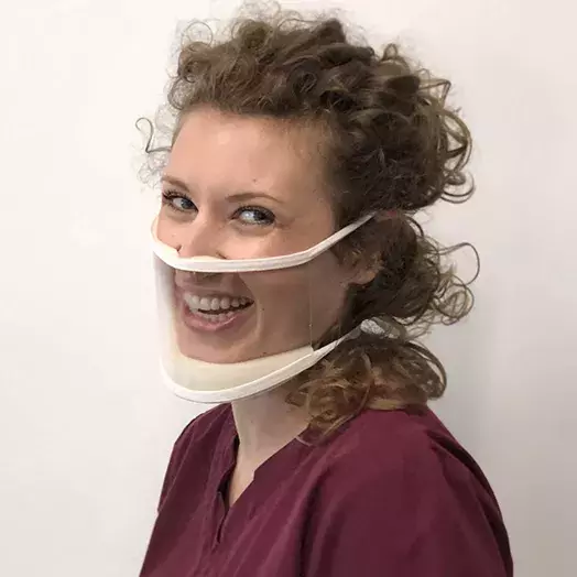 smiling woman wearking a mask that is semi-transparent