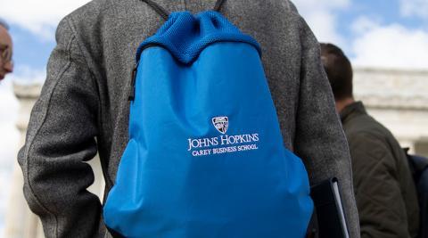 man wearing a johns hopkins carey business school branded backpack