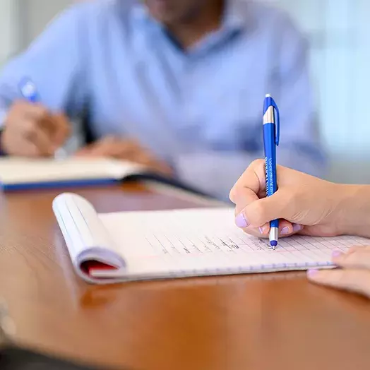 two students sitting at a table writing on a notepad