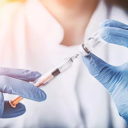 person holding a syringe and vaccinne bottle