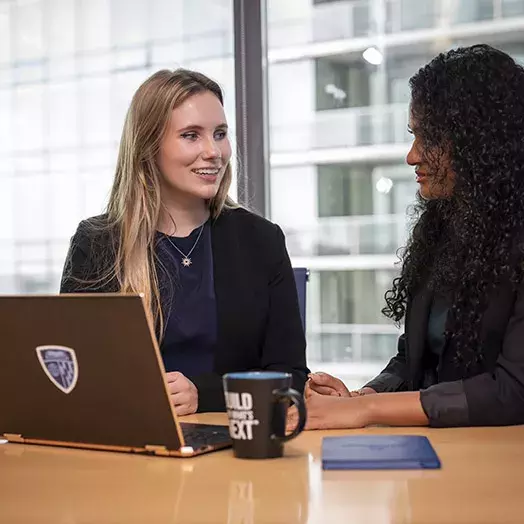 two students at a table with laptop