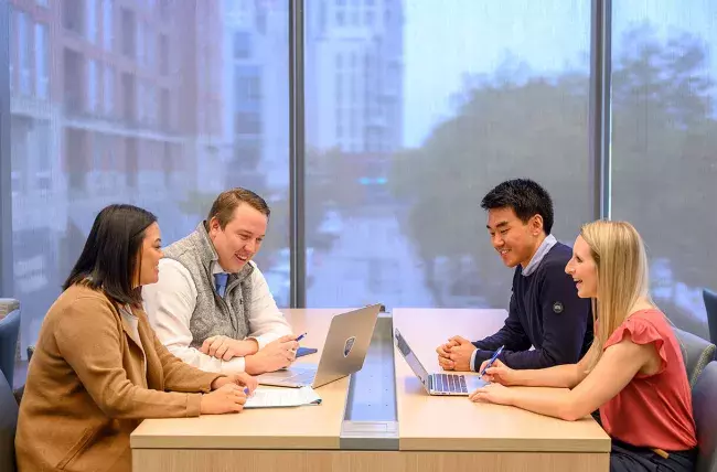 JHU carey business school students collaborate around a table, discussing the JHU Hexcite Healthcare technology innovation initiative 