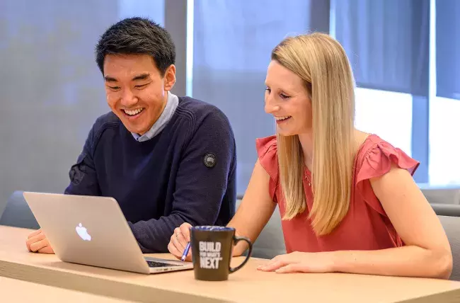 two students studying together with a laptop with a build for what's next mug