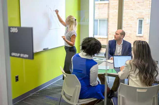 student writing on a dry erase board during Flexible MBA class