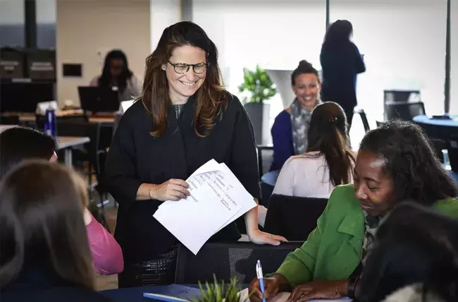 work area and a person holding papers interacting with small groups