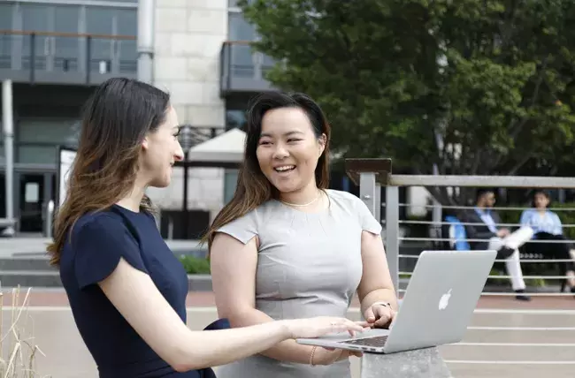 two students communicating out pleased with something on the laptop