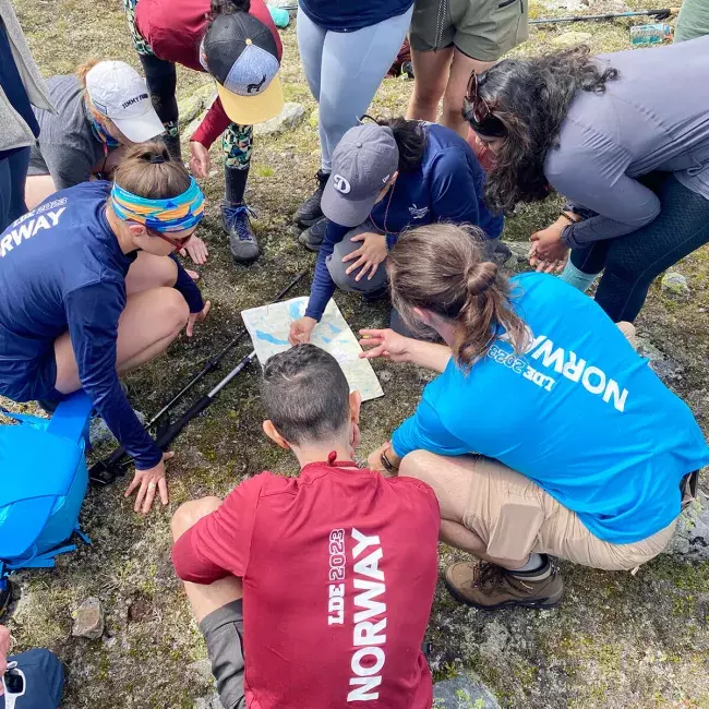 Norway group huddled around a map