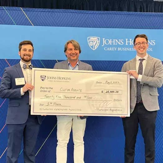 three students holding up a giant check