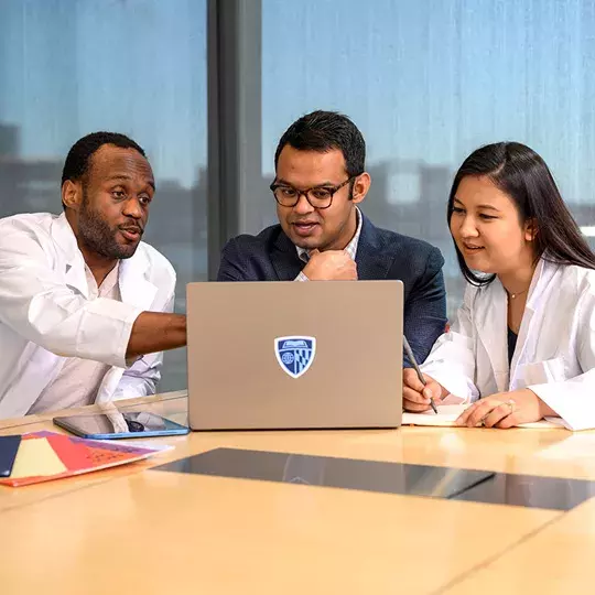 three students at a table with a laptop