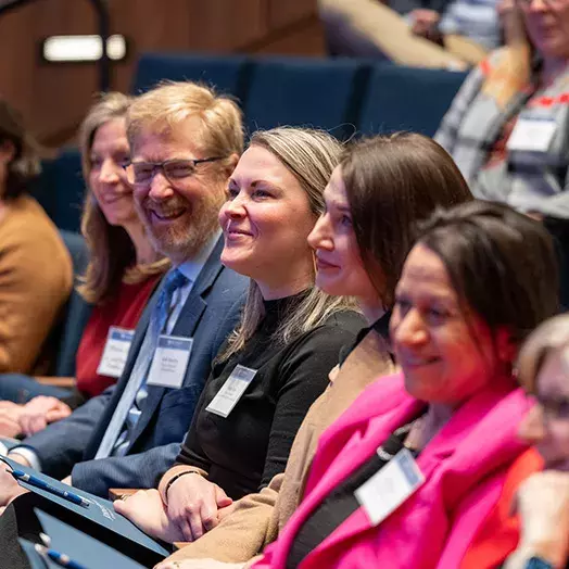 five people sitting in the audience at a conference