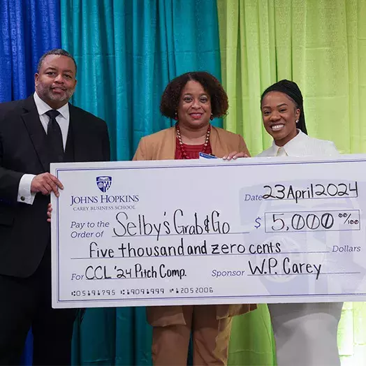 three people holding a large check