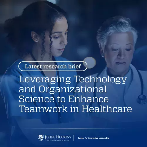 Two women, one in a white coat with a stethoscope around her neck and one with a lanyard around her neck, look at a glowing screen. The words "leveraging technology and organizational science to enhance teamwork in healthcare" appear in overlay.