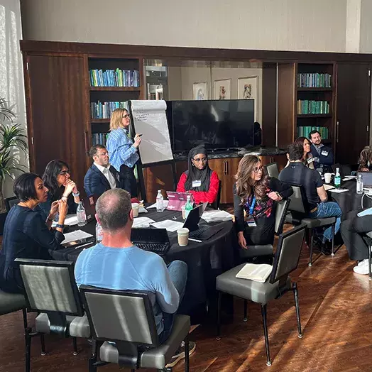 in person class in Phoenix with instructor at a large paper tablet with about nine student sitting casually, listening at two tables.