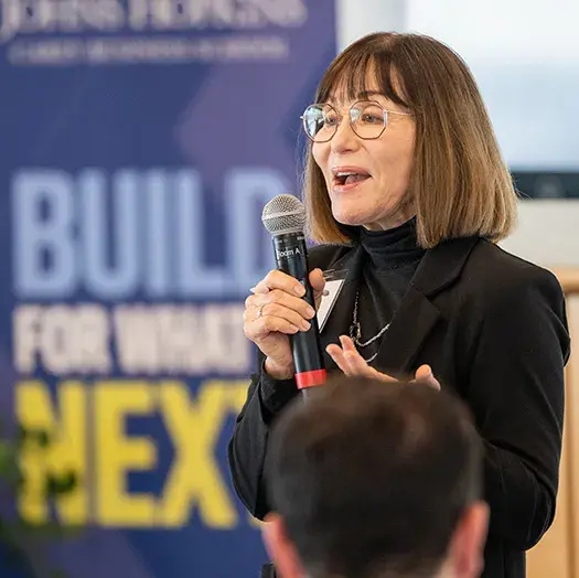 professor emeritus Kathleen Sutcliffe speaking with Build for what's next banner in background