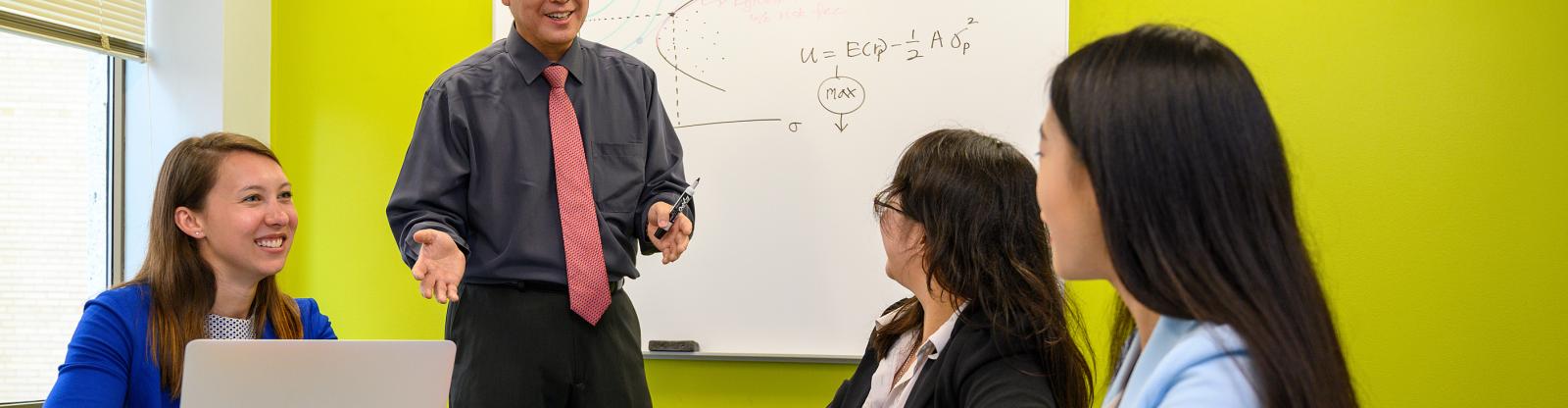 professor teaching three students in the classroom