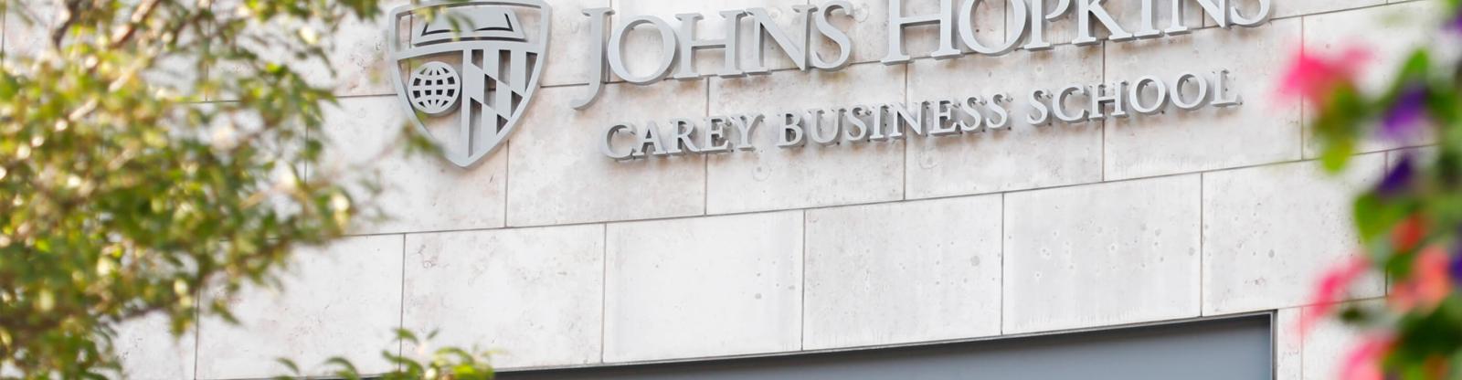 JHU Carey Business School front facade with tree and flowers during day